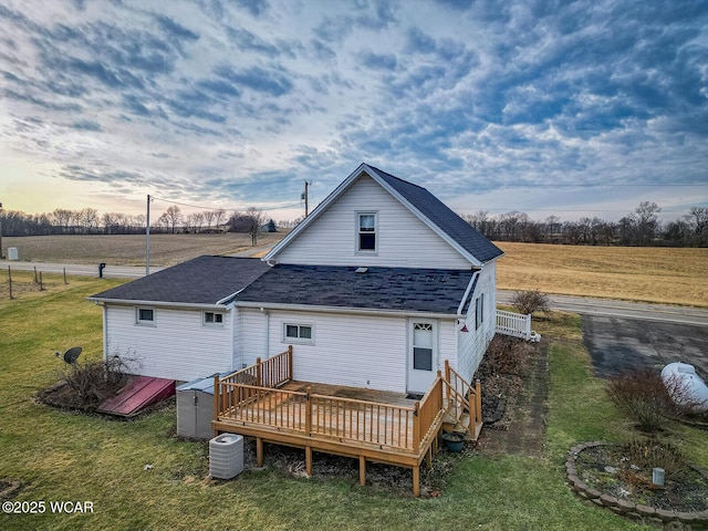 back house at dusk with a yard, cooling unit, a deck, and a rural view