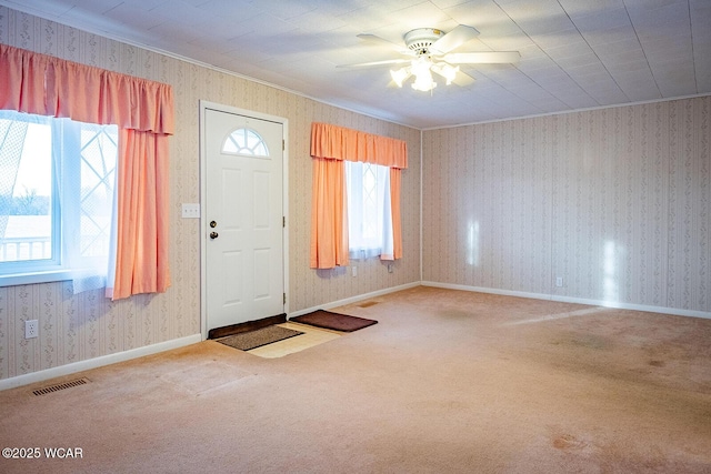 foyer entrance featuring ceiling fan, ornamental molding, and carpet flooring