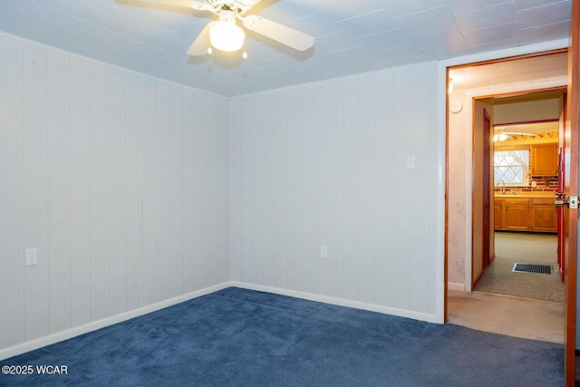 empty room with sink, ceiling fan, and dark colored carpet