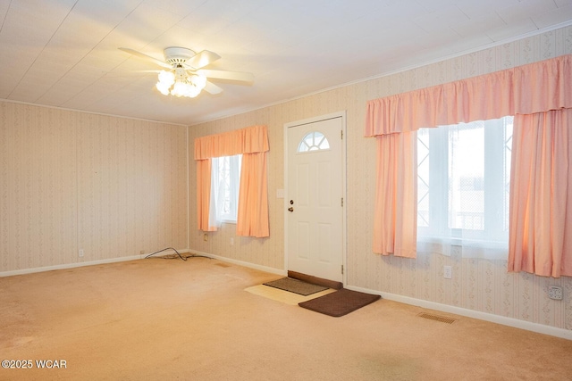 carpeted foyer with ornamental molding and ceiling fan