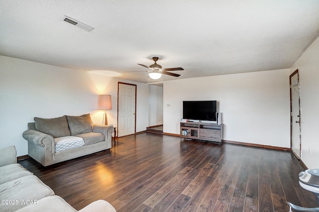 living room featuring ceiling fan, dark hardwood / wood-style flooring, and a textured ceiling