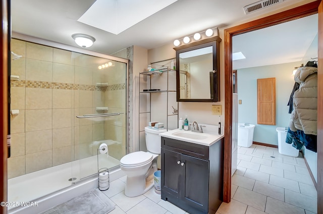 bathroom with tile patterned flooring, vanity, a shower with door, and a skylight