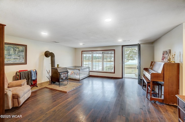 bedroom with dark hardwood / wood-style flooring, access to exterior, a textured ceiling, and a wood stove