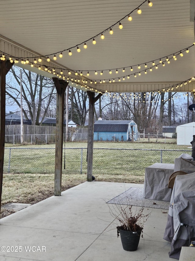 view of patio / terrace with an outbuilding, fence, and a storage unit