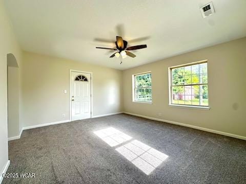 865 E 4th St, Lima, OH 45804 - empty room featuring arched walkways, a ceiling fan, dark carpet, and baseboards