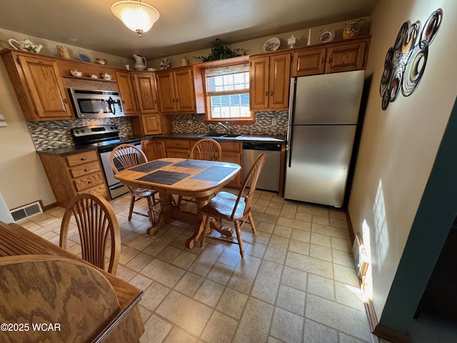 242 S Main St, Ottawa, OH 45875 - kitchen featuring stainless steel appliances, decorative backsplash, dark countertops, and brown cabinets
