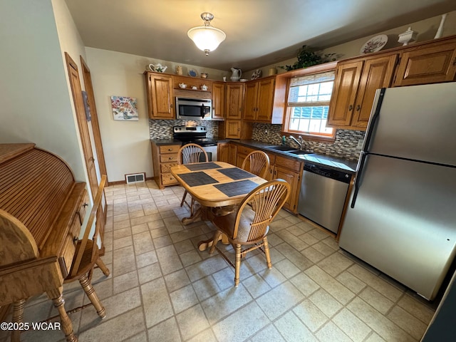 242 S Main St, Ottawa, OH 45875 - kitchen featuring appliances with stainless steel finishes, dark countertops, brown cabinetry, and decorative backsplash