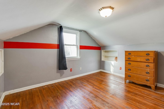 additional living space featuring lofted ceiling, hardwood / wood-style floors, and built in shelves