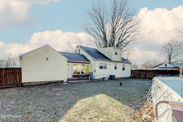 rear view of house featuring a lawn and central air condition unit