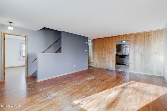 unfurnished living room with hardwood / wood-style floors and wood walls