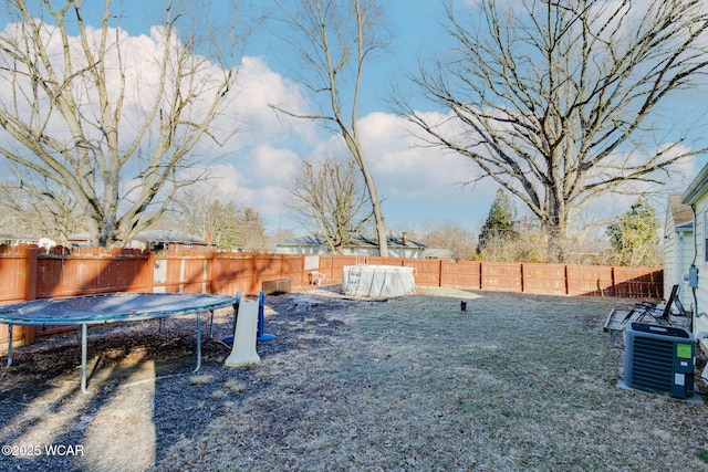 view of yard featuring a trampoline and central air condition unit