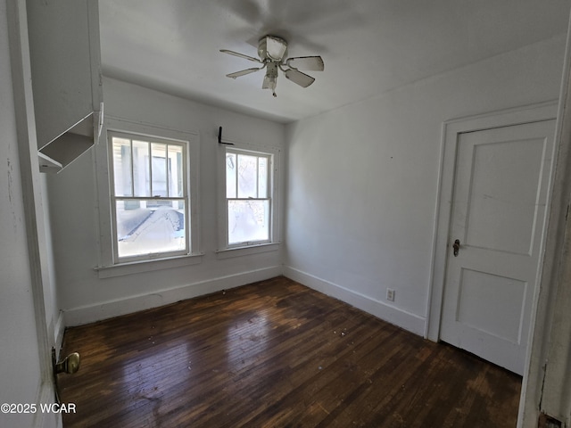 unfurnished room with baseboards, dark wood finished floors, and a ceiling fan