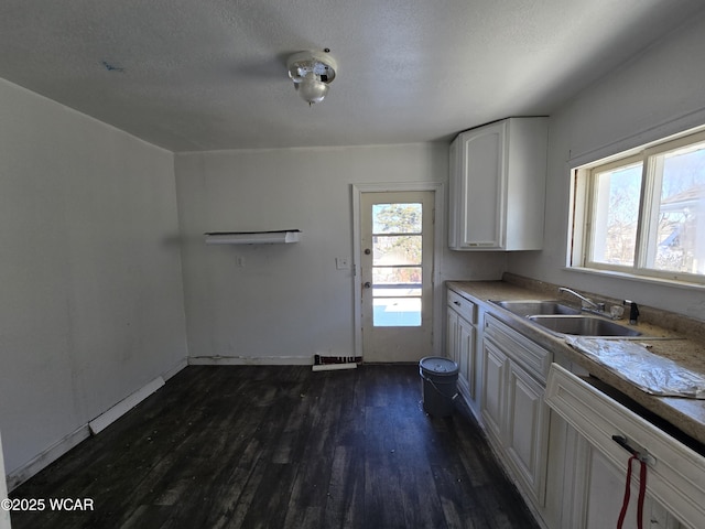 kitchen with light countertops, dark wood-type flooring, white cabinetry, a sink, and a textured ceiling