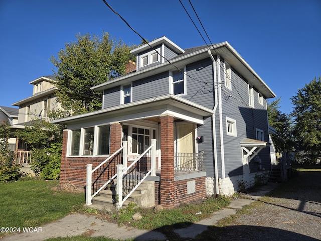 american foursquare style home with covered porch and brick siding