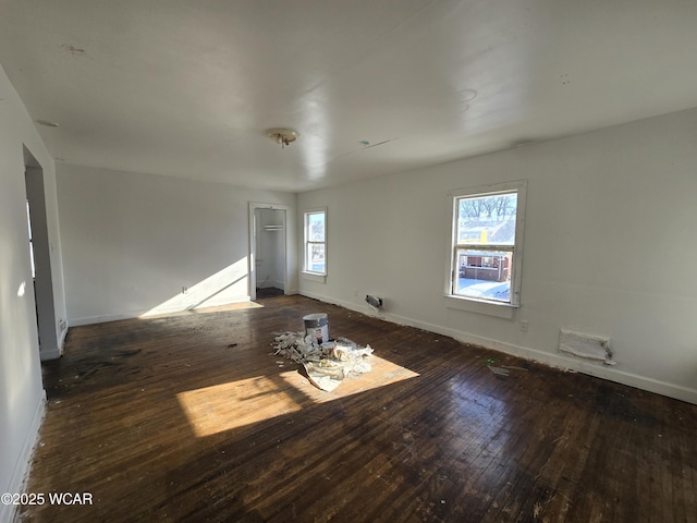 empty room featuring baseboards and dark wood finished floors