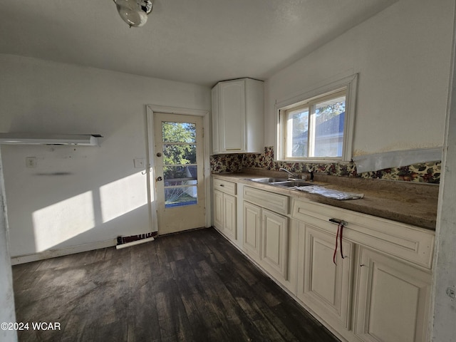 kitchen featuring dark wood finished floors, tasteful backsplash, dark countertops, white cabinets, and a sink