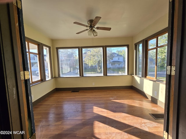 unfurnished sunroom with ceiling fan, plenty of natural light, and visible vents