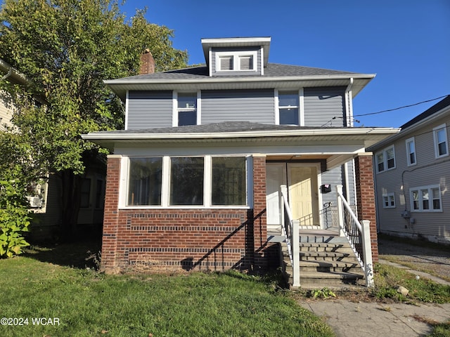 american foursquare style home featuring a front lawn and brick siding