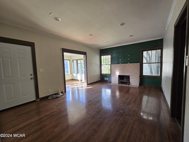 unfurnished living room featuring a brick fireplace, baseboards, crown molding, and dark wood-style flooring