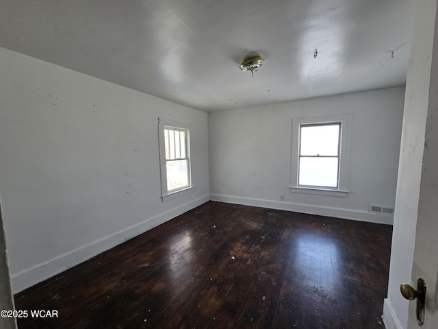 spare room with a healthy amount of sunlight, dark wood-style floors, and baseboards