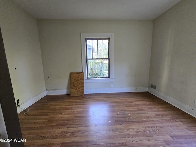 empty room featuring baseboards, visible vents, and wood finished floors