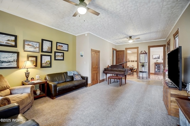 carpeted living area with crown molding, baseboards, and ceiling fan