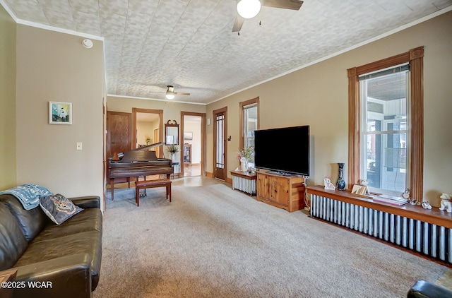 carpeted living room featuring ornamental molding and a ceiling fan