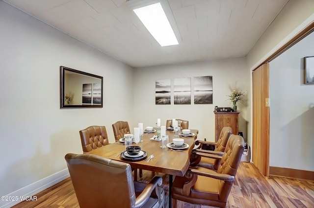 dining space with baseboards and wood finished floors