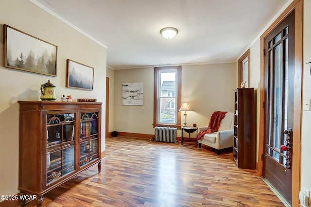 living area with baseboards, wood finished floors, ornamental molding, and radiator heating unit