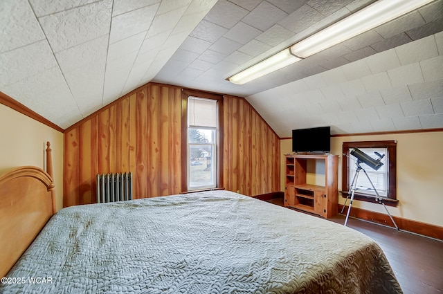 bedroom featuring radiator, baseboards, wood walls, lofted ceiling, and wood finished floors