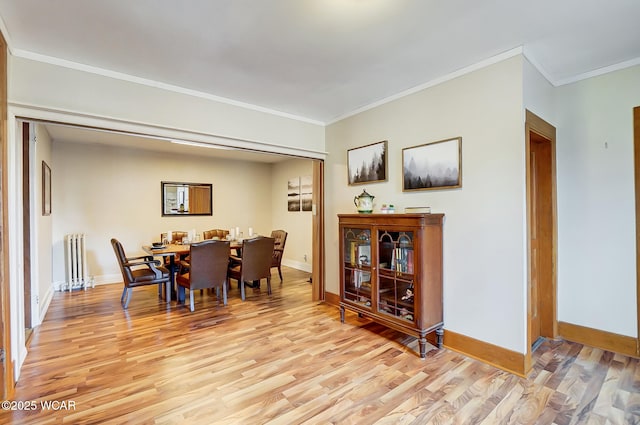 dining area featuring light wood finished floors, radiator, and baseboards