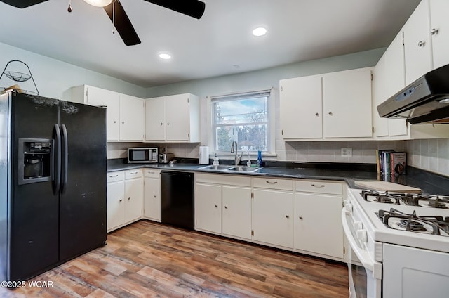 kitchen with a sink, dark countertops, black appliances, and wood finished floors