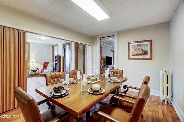 dining room featuring radiator, baseboards, and light wood finished floors