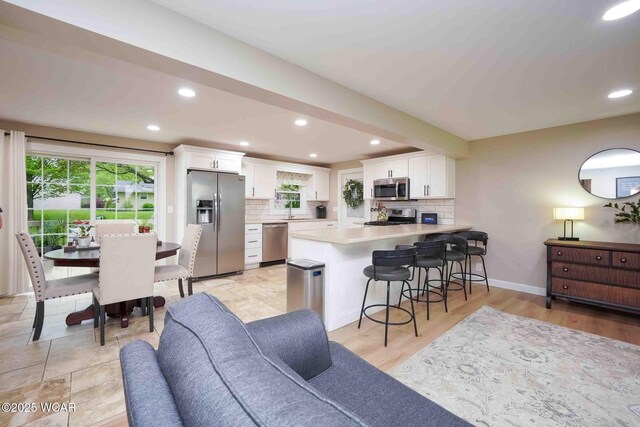2440 E Bluelick Rd, Lima, OH 45801 - kitchen featuring appliances with stainless steel finishes, a peninsula, backsplash, light countertops, and white cabinetry