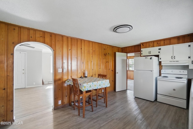 402 S Fifth St, Continental, OH 45831 - kitchen featuring wood walls, arched walkways, under cabinet range hood, wood finished floors, and white appliances