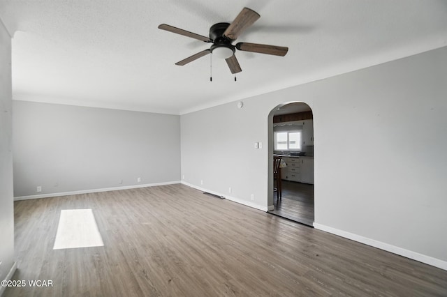 402 S Fifth St, Continental, OH 45831 - empty room with wood finished floors, a ceiling fan, baseboards, and arched walkways