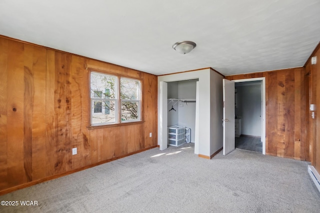 402 S Fifth St, Continental, OH 45831 - unfurnished bedroom with wood walls, a baseboard heating unit, a closet, baseboards, and carpet