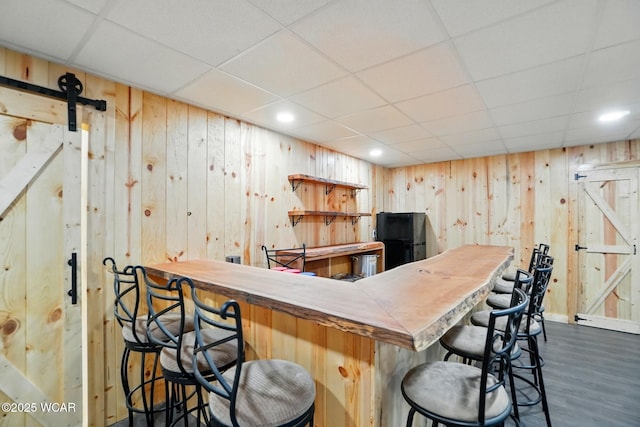 3467 Weldon Dr, Lima, OH 45806 - bar area with dark wood-style flooring, wood walls, a paneled ceiling, and baseboards