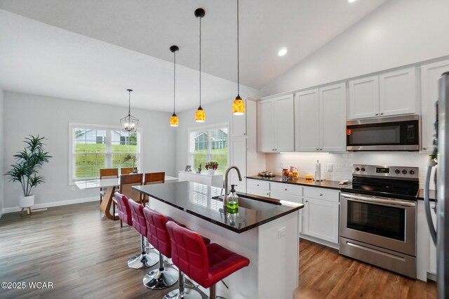 3467 Weldon Dr, Lima, OH 45806 - kitchen featuring stainless steel appliances, a sink, dark countertops, tasteful backsplash, and wood finished floors