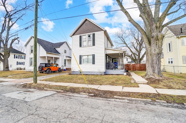 view of front of house with covered porch, fence, and a front lawn