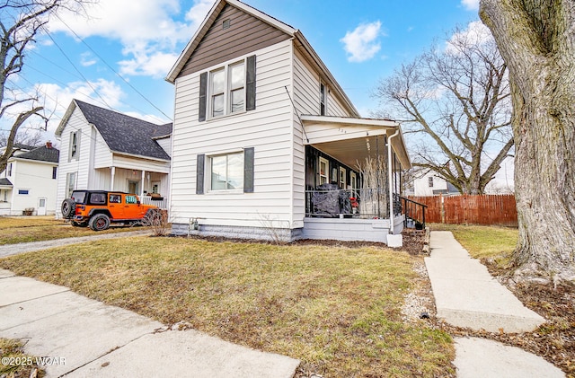 traditional-style home with a porch, fence, and a front lawn