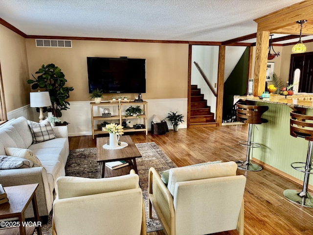 living room featuring a wainscoted wall, a textured ceiling, wood finished floors, and visible vents