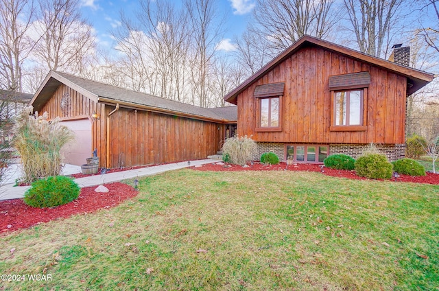 view of front of property featuring an attached garage, a chimney, a front lawn, and brick siding