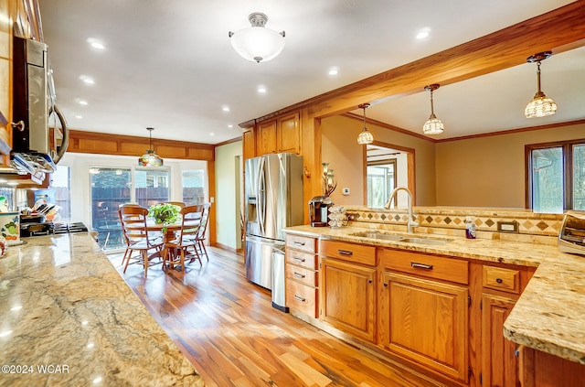 kitchen featuring light stone countertops, appliances with stainless steel finishes, a sink, and decorative light fixtures