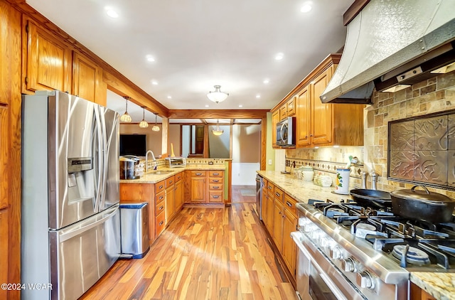 kitchen with appliances with stainless steel finishes, brown cabinets, custom range hood, and a sink