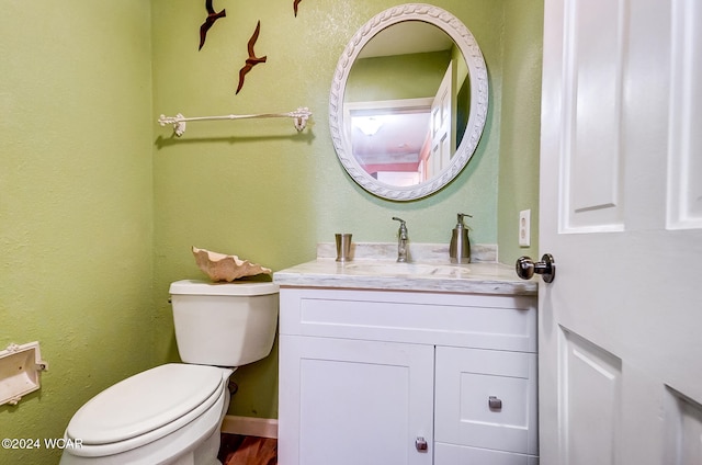 half bathroom featuring baseboards, vanity, and toilet