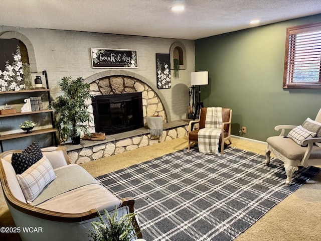 carpeted living area featuring baseboards, a textured ceiling, and a stone fireplace