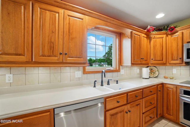 4042 Bur Oak Trl, Lima, OH 45807 - kitchen with appliances with stainless steel finishes, a sink, backsplash, light countertops, and brown cabinets