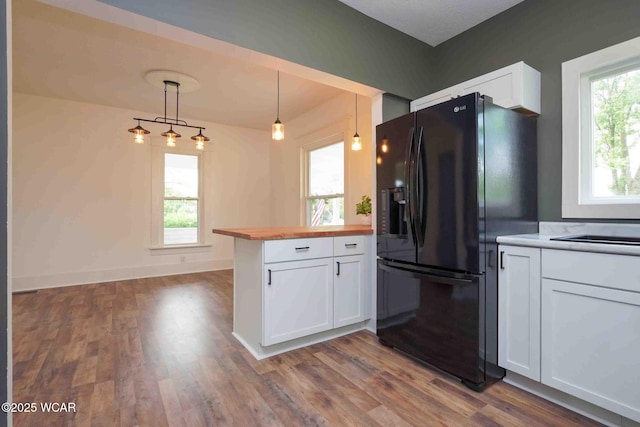 kitchen with black fridge with ice dispenser, a peninsula, butcher block countertops, dark wood-style flooring, and white cabinets