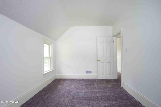 spare room with vaulted ceiling, carpet floors, and baseboards